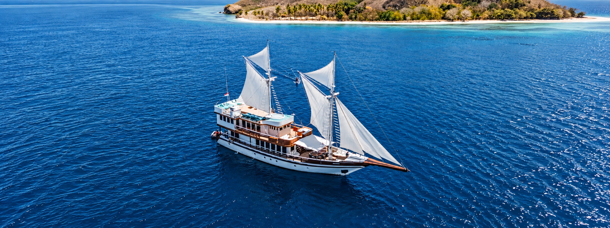 M/V KAYRA unter Segeln vor einer Insel, von oben gesehen